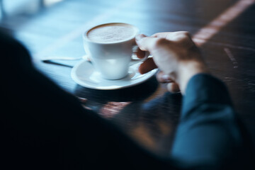 Cup of coffee on the table with white rice and a teaspoon of cafe mens hands.