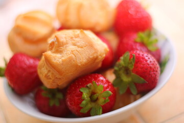 Fresh strawberries and profiteroles with ice cream in a white bowl