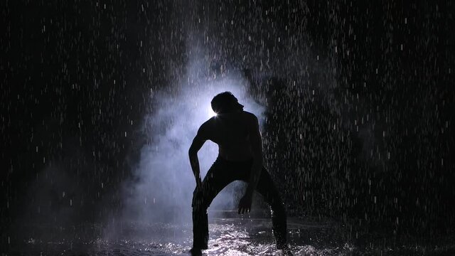 Emotional performance of modern contemporary choreography. Puffs of smoke hiding young man dancer on stage. Slow motion. Close up.