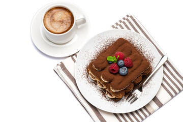portion of Classic tiramisu dessert with raspberries, blueberries and cup of fresh hot espresso isolated on white background - clipping path