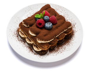 portion of Classic tiramisu dessert with raspberries and blueberries on ceramic plate isolated on white background - clipping path