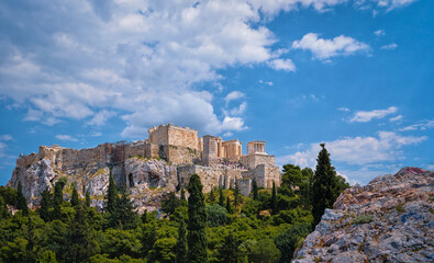 View of Acropolis hill from Areopagus hill on summer day with great clouds in blue sky, Athens, Greece. UNESCO heritage. Propylaea gate, Parthenon.