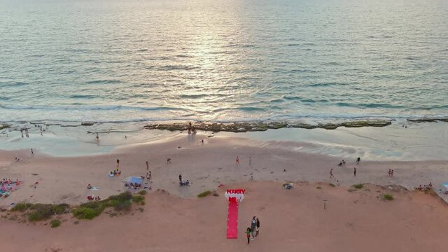 "Marry me" proposal sign on a picturesque beach at a sunset, 4k aerial drone view
