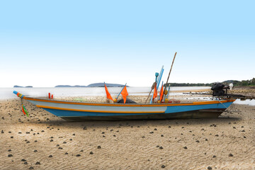 Fototapeta premium selective focus, a fisherman boat with flags and engine parking on the beach with blue sky in the background