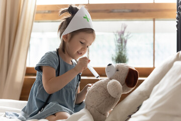 Little girl play in bedroom hold syringe gives injection caring about health of best soft bear...