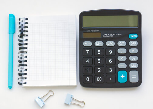 The calculator is on the table, next to an open empty notebook and a turquoise pen. Illustration of financial notes and mathematical calculations
