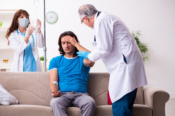 Two doctors visiting sick young man at home