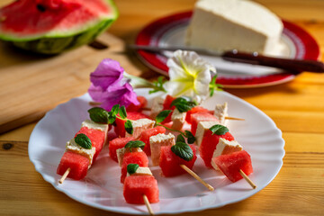 watermelon canapes with cheese sprinkled with mint on a plate