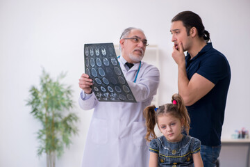 Young father and his daughter visiting old male doctor