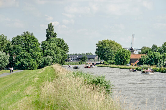 Schipluiden, The Netherlands, August 29, 2020: small boats on Zijde canal on a sunny day, a few metres higher than the bicycle path on the other side of the dike