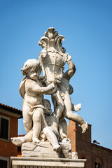 Putti fountain (Fontana dei Putti), Square of Miracles (Piazza dei Miracoli), Pisa, Tuscany, Italy. Three marble cherubs support the coat of arms of the city. Sculptor, Giovanni Antonio Cybei