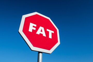 Stop sign in perspective view  with a text FAT against blue sky to lose weight and live healthy life
