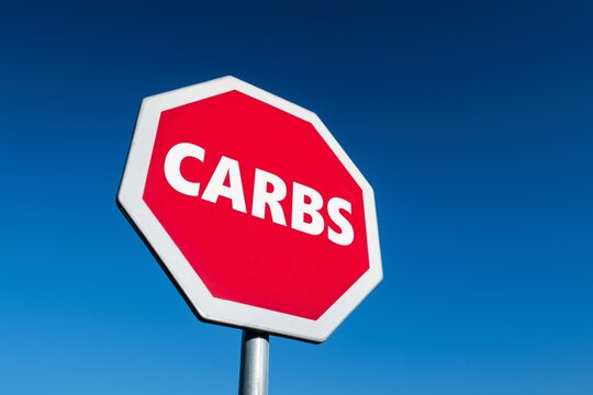 Stop sign in perspective view  with a text CARBS against blue sky to lose weight and live more healthy life and ketogenic diet
