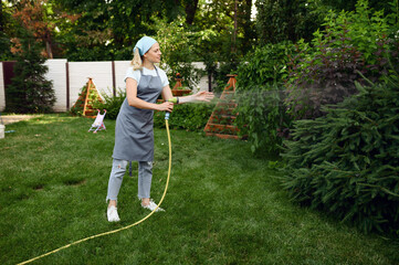 Woman with hose watering flowers in the garden