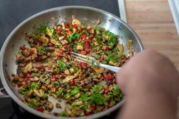 fried paprika and onions on a hot frying pan sprinkled with parsley, preparing a meal at home