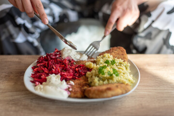 the person holds a fork and knife in her hand, in front of her, there is a homemade meal on the plate