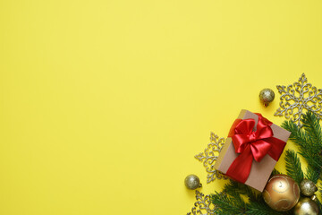 Christmas yellow background with fir, christmas balls and decor. Top view with space for copy.