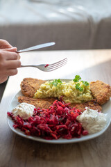 the person holds a fork and knife in her hand, in front of her, there is a homemade meal on the plate