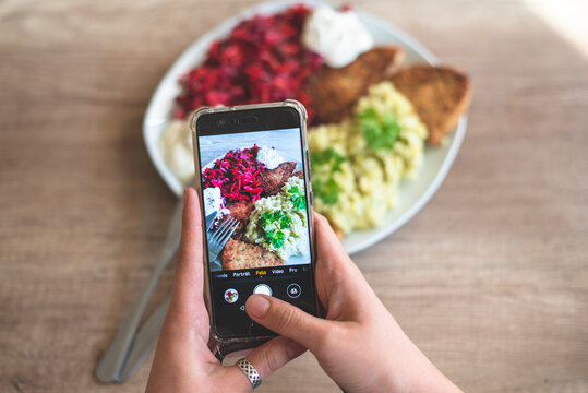 A food blogger takes photos of a home dinner with his phone