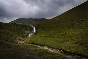 A nature landscape with a waterfall under a cloudy sky in the Isle of Skye, Scotland, United Kingdom