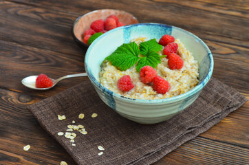 Delicious oatmeal porridge with ripe raspberries. Healthy and hearty Breakfast. The concept of diet and vegetarian food for a slim figure lifestyle