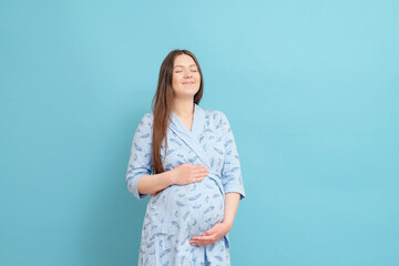 young happy pregnant woman on blue background in blue home bathrobe