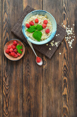 Delicious and hearty breakfast oatmeal porridge with raspberries in a beautiful ceramic bowl. The concept of healthy food, diet, organic nutrition and lifestyle. Space for text and design
