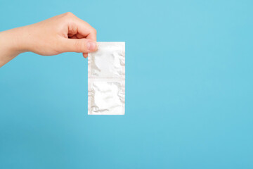 condom in female hand on blue background