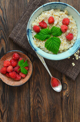 Delicious and hearty breakfast oatmeal porridge with raspberries in a beautiful ceramic bowl. The concept of healthy food, diet, organic nutrition and lifestyle. Space for text and design