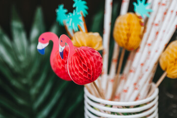 Colorful tropical party decorations. Flamingo and pineapple decorations. Paper straws and cups. 