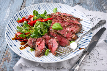 Traditional Italian barbecue tagliata with corn salad and paprika offered as close-up on a design plate