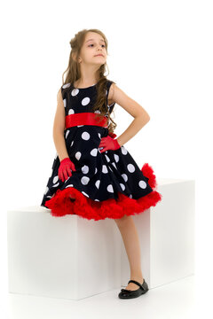 Girl in Polka Dot Dress, Red Gloves and Bow Standing Looking Awa.