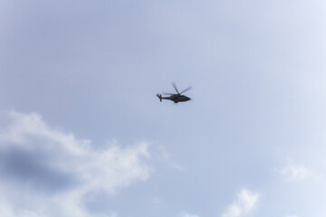 Helicopter in the distance in light sky with cloud. Soft focus.