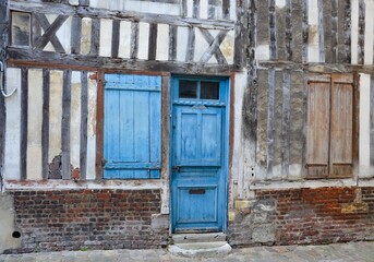 Obraz na płótnie Canvas Closeup of a medieval timbered house in the old town of the city of Honfleur in the county of Calvados in Normandy, France, built of stone and wood, turquoise doors and shutters, summer