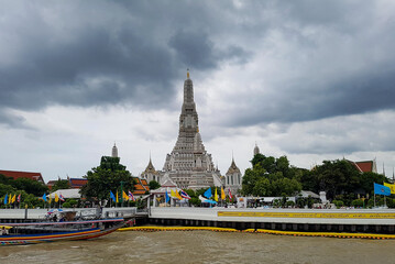 Naklejka premium Wat Arun Bangkok city by bad grey weather on holiday backpacking tour with clouds in the sky