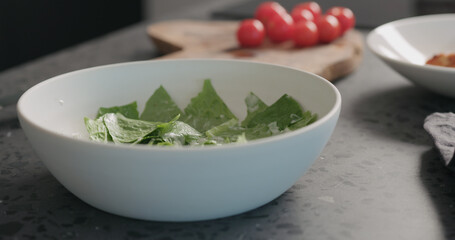 Making caesar salad with chicken and cherry tomatoes in white bowl