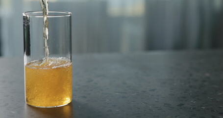 pour pear cider into glass on terrazzo countertop with copy space
