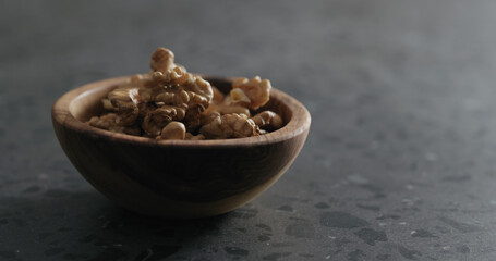 walnut kernels in wooden bowl on terrazzo countertop