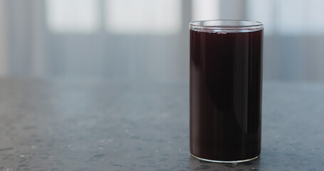 blackcurrant juice in a glass on concrete countertop with copy space