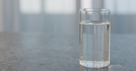 clean fresh sparkling water in beaker glass on concrete countertop