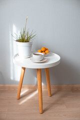 Coffee cup with plant flower on wooden coffee table in white living room interior