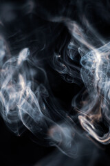 White smoke from incense stick isolated against dark background