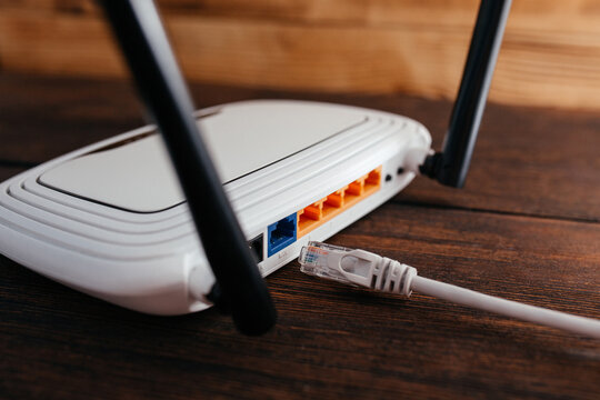 An Unconnected LAN Cable To A Router On A Dark Wooden Table. Lack Of High-speed Wi-fi Internet. Internet Connection Problems