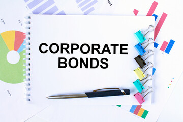 Notepad with text Corporate Bonds, paper clips, blue pen on financial diagrams