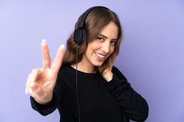 Young woman over isolated purple background listening music and singing