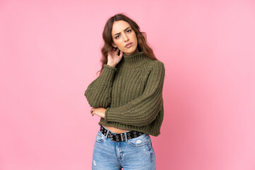Young woman over isolated pink background having doubts