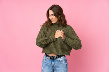 Young woman over isolated pink background having a pain in the heart