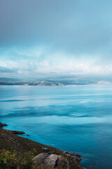 Rocky sea at evening with a blue cloudy sky at the end of Camino de Santiago - Finisterre, Galicia, Spain