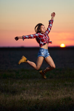 Young woman jumping for joy at sunset