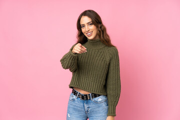 Young woman over isolated pink background points finger at you with a confident expression